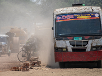 People are walking along a dusty, busy road in Dhaka, Bangladesh, on April 26, 2024. (