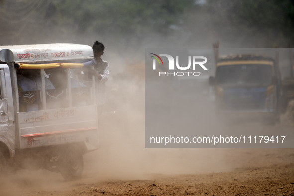 People are walking along a dusty, busy road in Dhaka, Bangladesh, on April 26, 2024. 