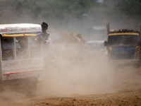 People are walking along a dusty, busy road in Dhaka, Bangladesh, on April 26, 2024. (