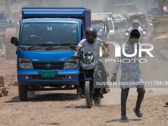 People are walking along a dusty, busy road in Dhaka, Bangladesh, on April 26, 2024. (