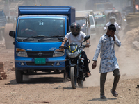 People are walking along a dusty, busy road in Dhaka, Bangladesh, on April 26, 2024. (