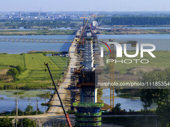 Workers are carrying out the construction of the steel pier bridge and the lower structure of the bridge across three river sections at the...