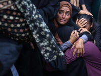 Palestinians are mourning by the bodies of relatives who were killed in an Israeli bombardment, at the al-Aqsa hospital in Deir Balah in the...