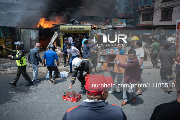 Shop owners are salvaging belongings as a fire spreads from a vehicle workshop to adjacent shops in Sankhamul, Kathmandu, causing extensive...