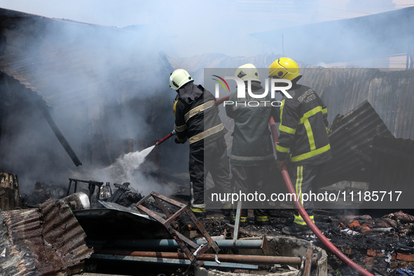 Firefighters and Nepal Police attempt to control the fire that engulfed a vehicle service center in Kathmandu, Nepal, on April 28, 2024.