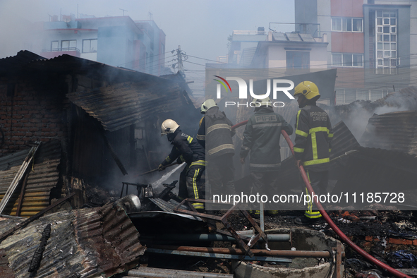 Firefighters and Nepal Police attempt to control the fire that engulfed a vehicle service center in Kathmandu, Nepal, on April 28, 2024.