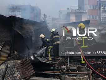 Firefighters and Nepal Police attempt to control the fire that engulfed a vehicle service center in Kathmandu, Nepal, on April 28, 2024.(