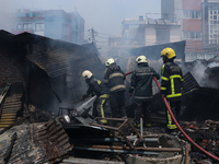 Firefighters and Nepal Police attempt to control the fire that engulfed a vehicle service center in Kathmandu, Nepal, on April 28, 2024.(