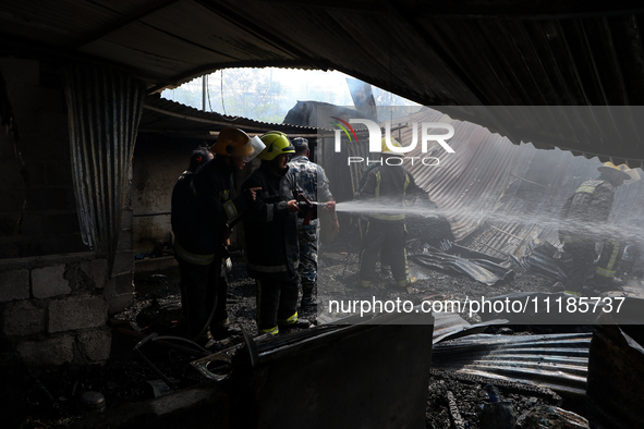 Firefighters and Nepal Police attempt to control the fire that engulfed a vehicle service center in Kathmandu, Nepal, on April 28, 2024.