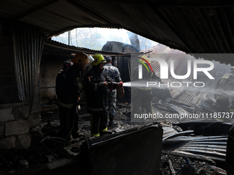 Firefighters and Nepal Police attempt to control the fire that engulfed a vehicle service center in Kathmandu, Nepal, on April 28, 2024.(