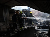 Firefighters and Nepal Police attempt to control the fire that engulfed a vehicle service center in Kathmandu, Nepal, on April 28, 2024.(