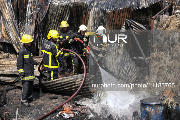 Firefighters and Nepal Police attempt to control the fire that engulfed a vehicle service center in Kathmandu, Nepal, on April 28, 2024.