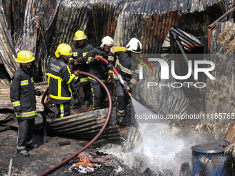 Firefighters and Nepal Police attempt to control the fire that engulfed a vehicle service center in Kathmandu, Nepal, on April 28, 2024.(