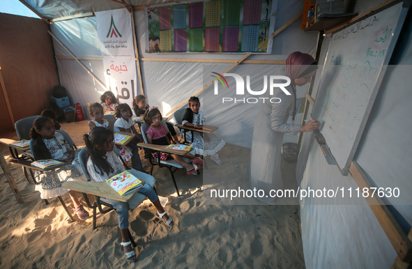 Palestinian children are attending class at a makeshift school in a camp for displaced Palestinians in Deir El-Balah, in the central Gaza St...