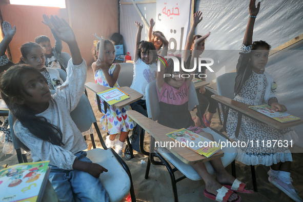 Palestinian children are attending class at a makeshift school in a camp for displaced Palestinians in Deir El-Balah, in the central Gaza St...