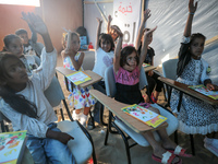 Palestinian children are attending class at a makeshift school in a camp for displaced Palestinians in Deir El-Balah, in the central Gaza St...