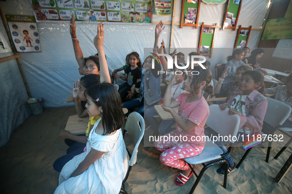 Palestinian children are attending class at a makeshift school in a camp for displaced Palestinians in Deir El-Balah, in the central Gaza St...