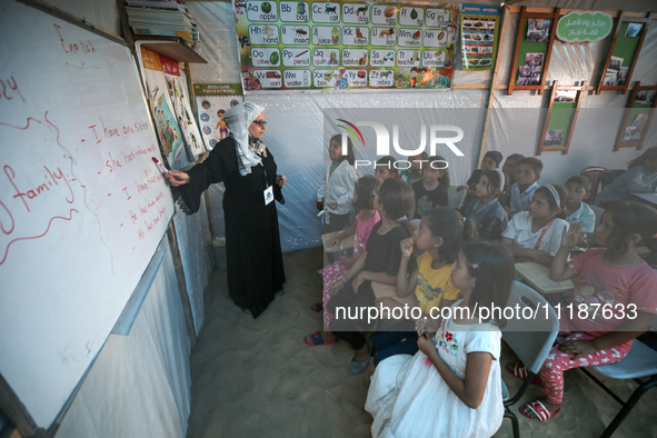 Palestinian children are attending class at a makeshift school in a camp for displaced Palestinians in Deir El-Balah, in the central Gaza St...