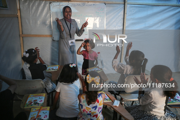 Palestinian children are attending class at a makeshift school in a camp for displaced Palestinians in Deir El-Balah, in the central Gaza St...