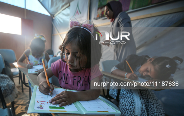 Palestinian children are attending class at a makeshift school in a camp for displaced Palestinians in Deir El-Balah, in the central Gaza St...