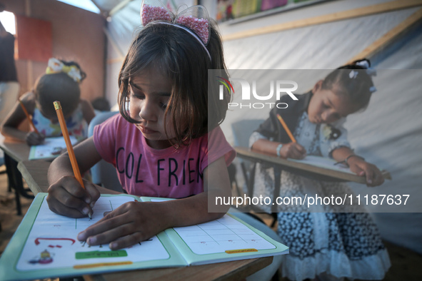 Palestinian children are attending class at a makeshift school in a camp for displaced Palestinians in Deir El-Balah, in the central Gaza St...