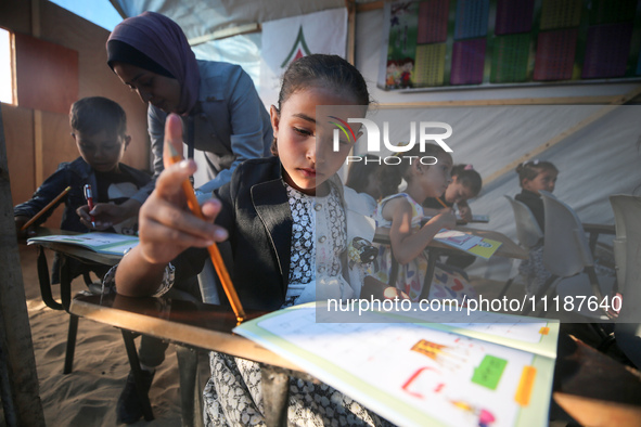 Palestinian children are attending class at a makeshift school in a camp for displaced Palestinians in Deir El-Balah, in the central Gaza St...