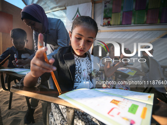 Palestinian children are attending class at a makeshift school in a camp for displaced Palestinians in Deir El-Balah, in the central Gaza St...