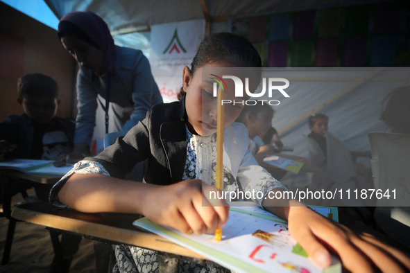 Palestinian children are attending class at a makeshift school in a camp for displaced Palestinians in Deir El-Balah, in the central Gaza St...