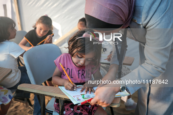 Palestinian children are attending class at a makeshift school in a camp for displaced Palestinians in Deir El-Balah, in the central Gaza St...