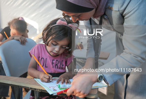 Palestinian children are attending class at a makeshift school in a camp for displaced Palestinians in Deir El-Balah, in the central Gaza St...