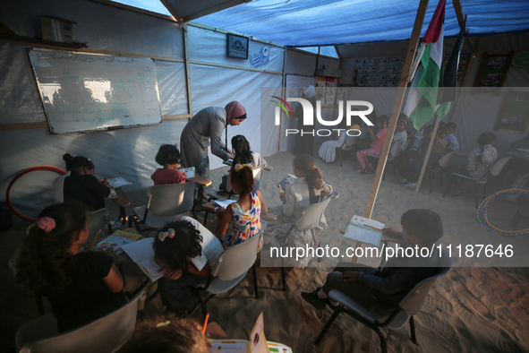 Palestinian children are attending class at a makeshift school in a camp for displaced Palestinians in Deir El-Balah, in the central Gaza St...