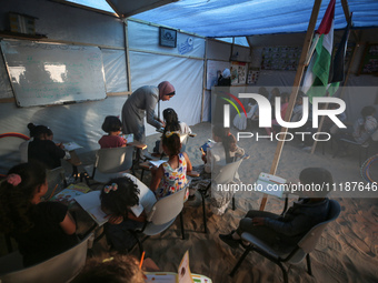 Palestinian children are attending class at a makeshift school in a camp for displaced Palestinians in Deir El-Balah, in the central Gaza St...