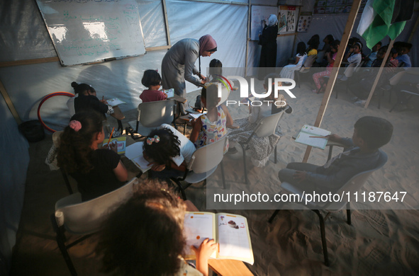 Palestinian children are attending class at a makeshift school in a camp for displaced Palestinians in Deir El-Balah, in the central Gaza St...