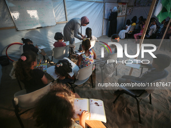 Palestinian children are attending class at a makeshift school in a camp for displaced Palestinians in Deir El-Balah, in the central Gaza St...