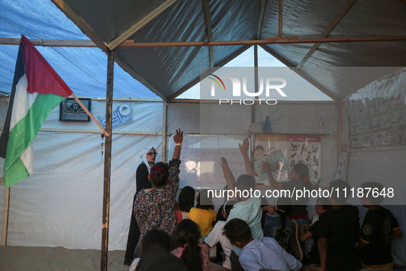 Palestinian children are attending class at a makeshift school in a camp for displaced Palestinians in Deir El-Balah, in the central Gaza St...