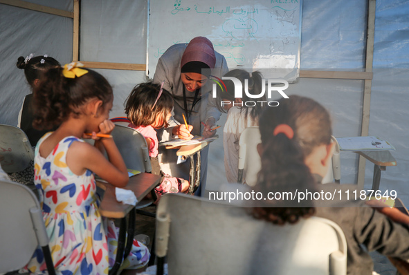 Palestinian children are attending class at a makeshift school in a camp for displaced Palestinians in Deir El-Balah, in the central Gaza St...