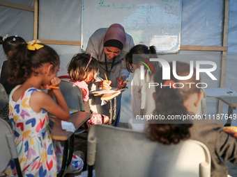 Palestinian children are attending class at a makeshift school in a camp for displaced Palestinians in Deir El-Balah, in the central Gaza St...