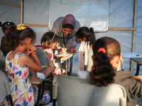 Palestinian children are attending class at a makeshift school in a camp for displaced Palestinians in Deir El-Balah, in the central Gaza St...