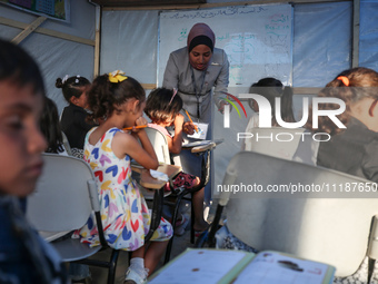 Palestinian children are attending class at a makeshift school in a camp for displaced Palestinians in Deir El-Balah, in the central Gaza St...