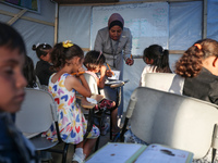 Palestinian children are attending class at a makeshift school in a camp for displaced Palestinians in Deir El-Balah, in the central Gaza St...