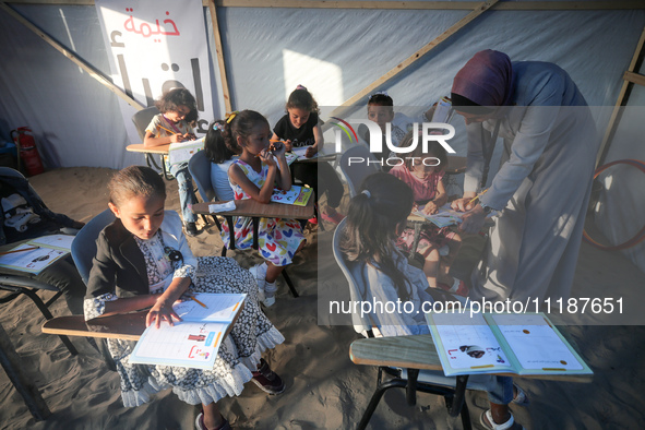 Palestinian children are attending class at a makeshift school in a camp for displaced Palestinians in Deir El-Balah, in the central Gaza St...