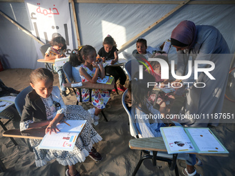 Palestinian children are attending class at a makeshift school in a camp for displaced Palestinians in Deir El-Balah, in the central Gaza St...