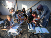 Palestinian children are attending class at a makeshift school in a camp for displaced Palestinians in Deir El-Balah, in the central Gaza St...