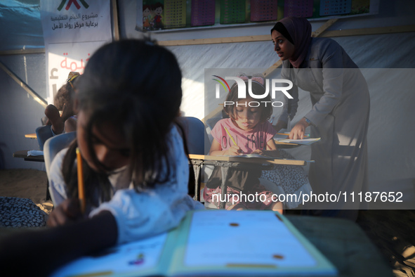 Palestinian children are attending class at a makeshift school in a camp for displaced Palestinians in Deir El-Balah, in the central Gaza St...