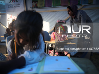 Palestinian children are attending class at a makeshift school in a camp for displaced Palestinians in Deir El-Balah, in the central Gaza St...