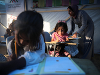 Palestinian children are attending class at a makeshift school in a camp for displaced Palestinians in Deir El-Balah, in the central Gaza St...