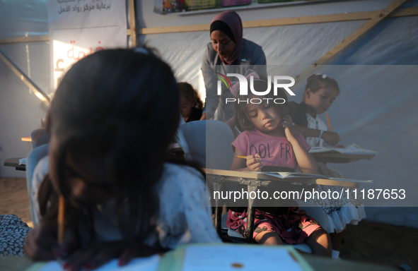 Palestinian children are attending class at a makeshift school in a camp for displaced Palestinians in Deir El-Balah, in the central Gaza St...