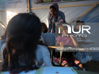 Palestinian children are attending class at a makeshift school in a camp for displaced Palestinians in Deir El-Balah, in the central Gaza St...