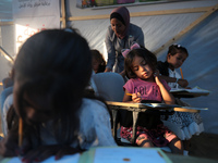 Palestinian children are attending class at a makeshift school in a camp for displaced Palestinians in Deir El-Balah, in the central Gaza St...