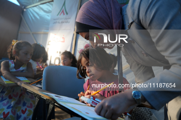 Palestinian children are attending class at a makeshift school in a camp for displaced Palestinians in Deir El-Balah, in the central Gaza St...